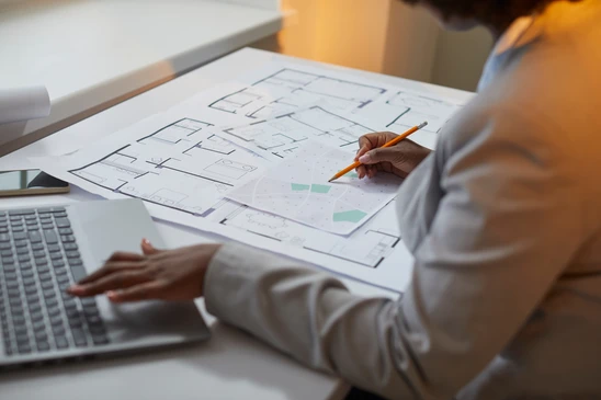 Professionnel en architecture travaillant sur plans techniques à son bureau